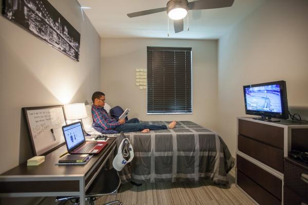 Male student studying on bed in residence hall