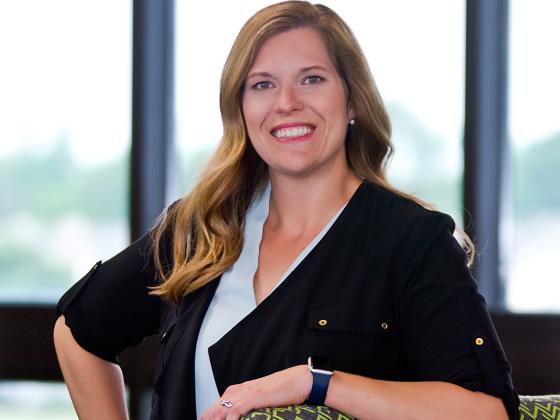Anna Workman, posing by leaning with one elbow on a green chair.